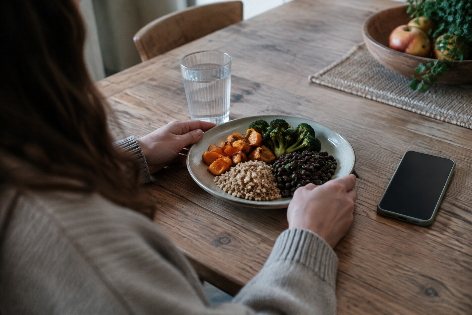Adult preparing a balanced meal beside a smartphone, illustrating support after stopping GLP-1 treatment